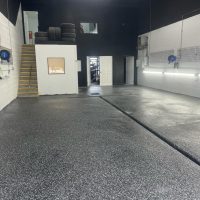 Image depicts flake epoxy flooring installed in a car detailing shop.