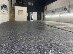 Image depicts flake epoxy flooring installed in a car detailing shop.