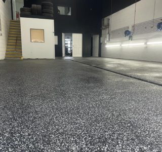 Image depicts flake epoxy flooring installed in a car detailing shop.
